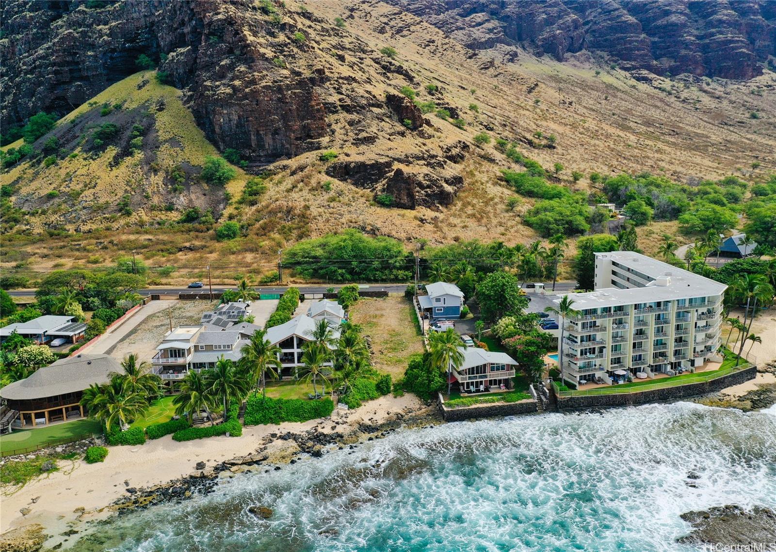 Resort buildings along a sandy beach with mountains in the background, showcasing a tropical destination ideal for relaxation and travel.